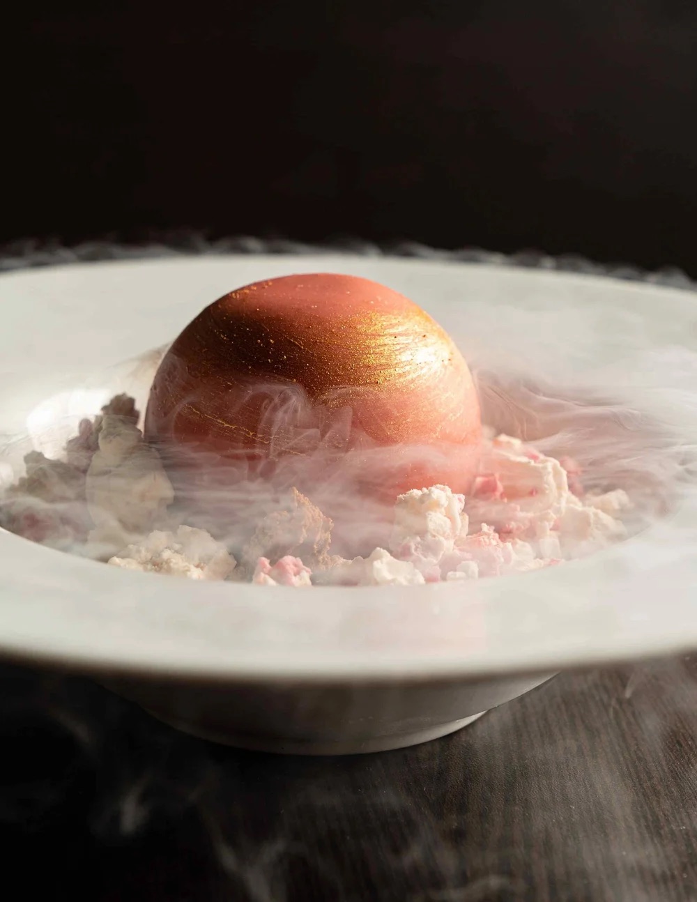 A gold-dusted dome dessert under drifting mist